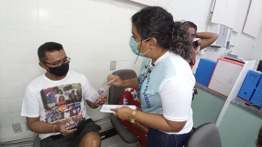 Segurado recebe material informativo das mãos de assistente social no IPMB.